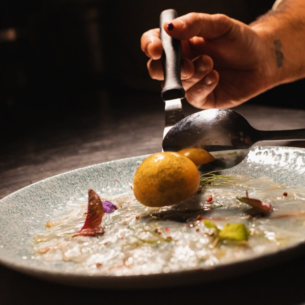 person holding stainless steel spoon and fork eating on black table